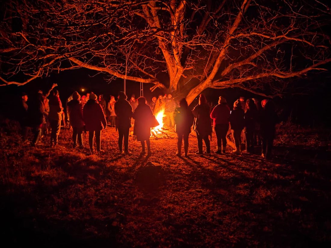Una ronda alrededor del fogón, de noche, bajo un árbol