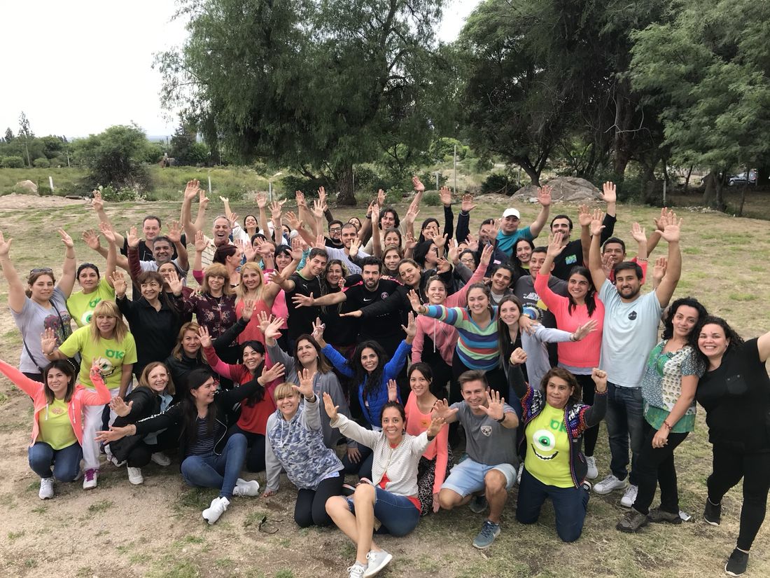 Un grupo grande celebra con los brazos en alto en el campo