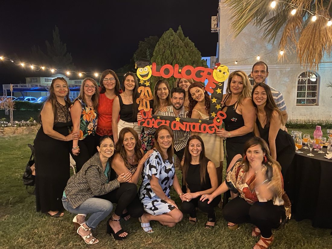 Egresadas festejan de noche junto al cartel Lo logré, soy coach ontológico