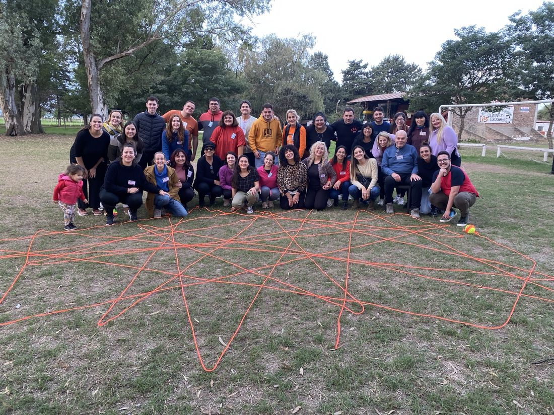Un grupo posa detrás de una red de hilo naranja tendida sobre el pasto