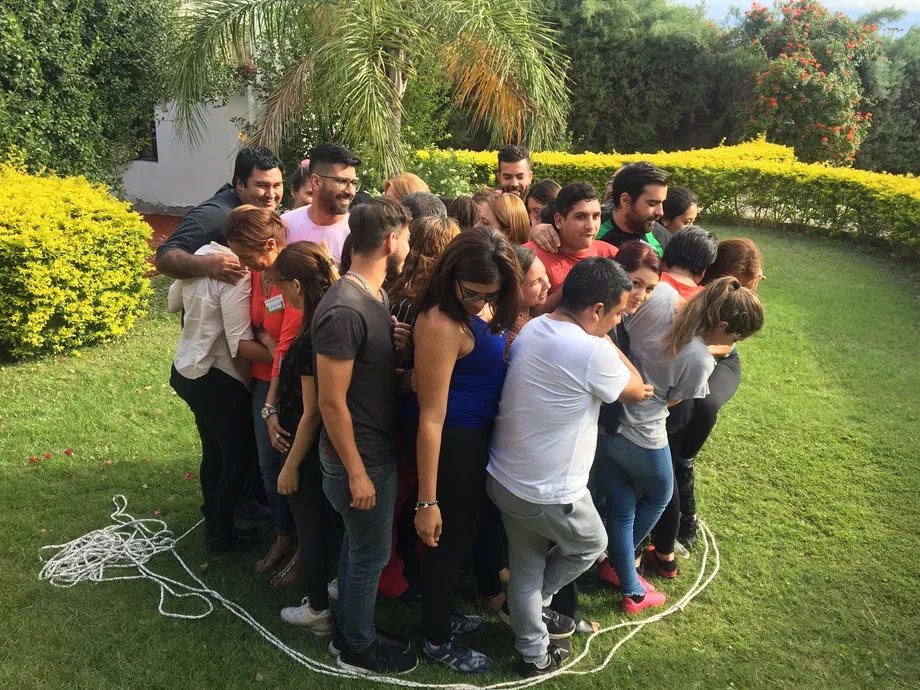 Un equipo entero abrazado dentro de un círculo de soga durante una dinámica